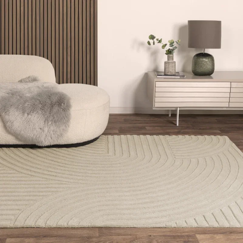 Cream geometric rug on wooden floor with curved sofa and modern sideboard in living room
