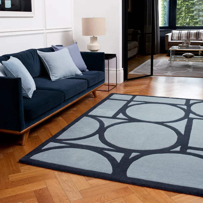 Modern navy blue sofa with light blue cushions and geometric pattern area rug in living room