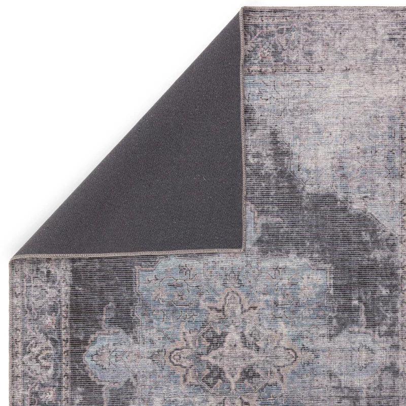 Corner of vintage patterned area rug with blue and grey tones on white background