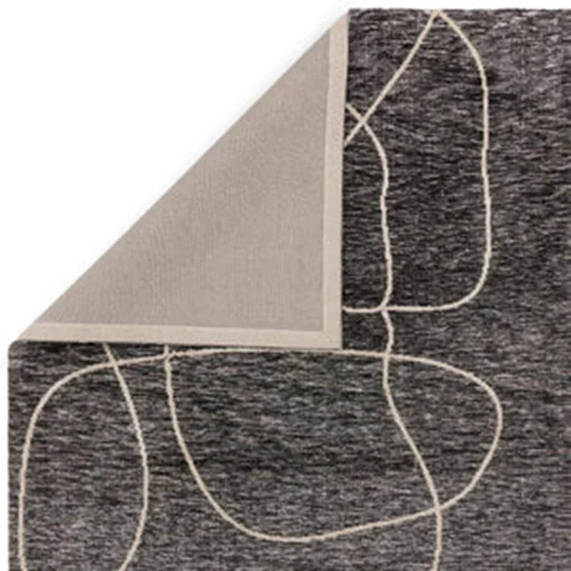 Grey area rug with white abstract lines, corner folded to show backing detail