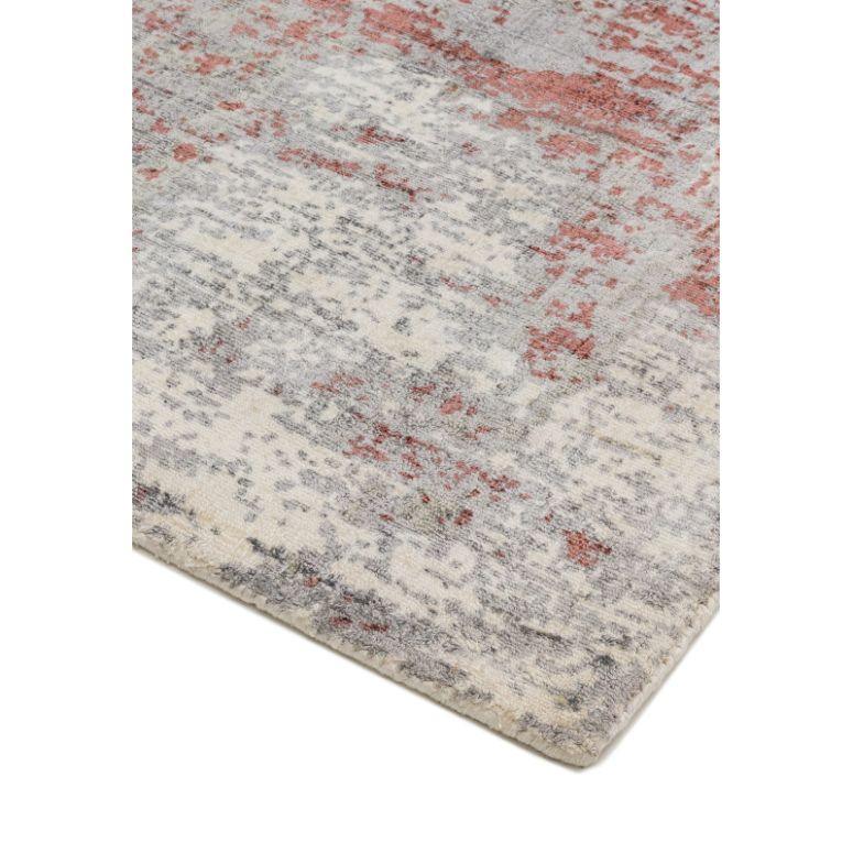 Corner view of modern area rug with grey and rust abstract pattern