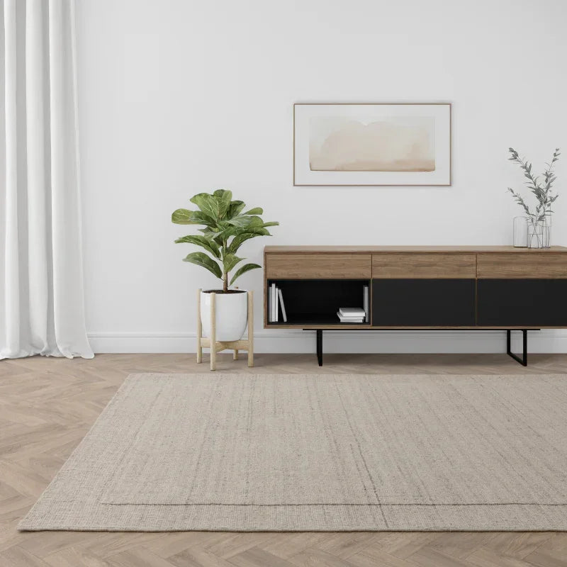 Neutral modern area rug on wooden floor with sideboard and indoor plant