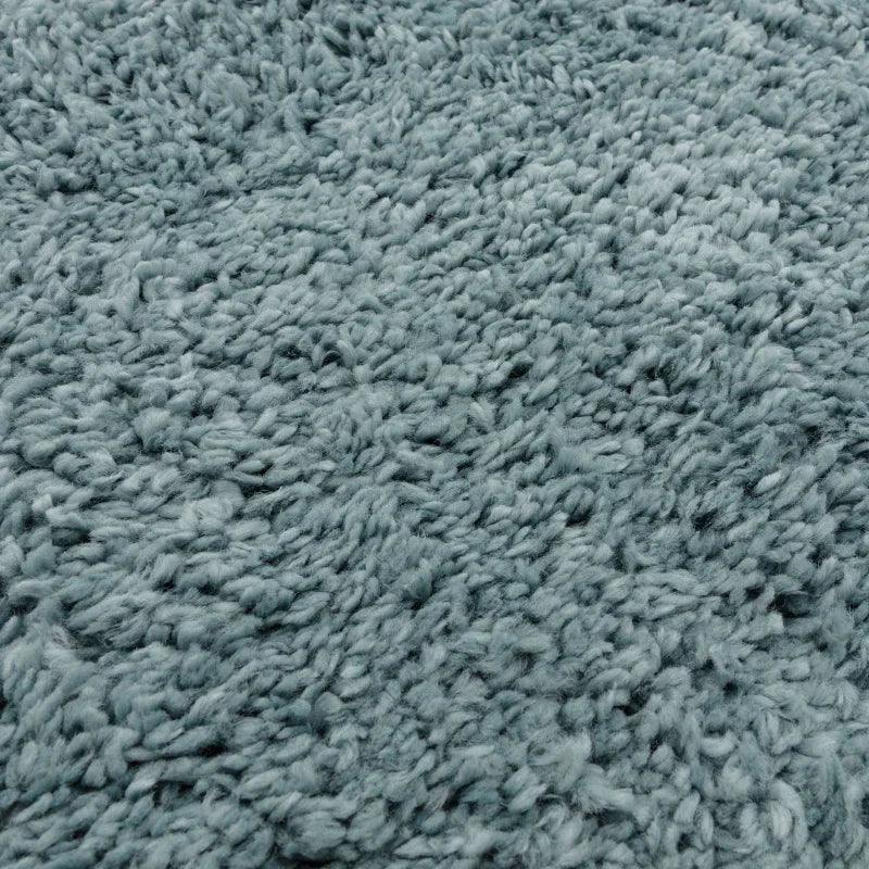 Close up of blue shaggy rug texture highlighting soft pile and woven fibres