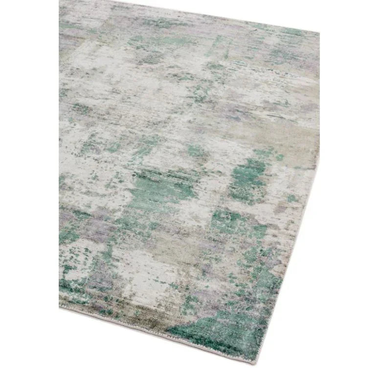 Modern area rug with abstract green and grey pattern, corner view on white background