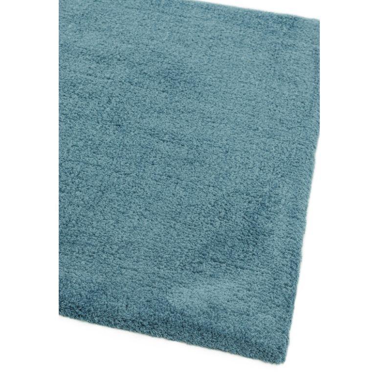 Teal blue area rug with soft textured surface, corner view on white background