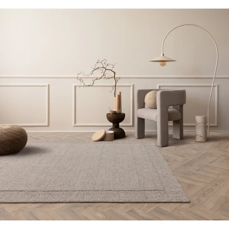 Modern beige living room with textured rug, accent chair, and arched floor lamp
