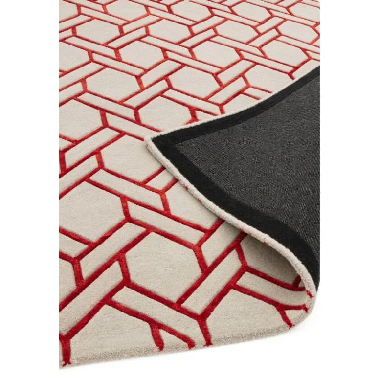 Geometric area rug with red pattern on cream background, corner folded to show underside