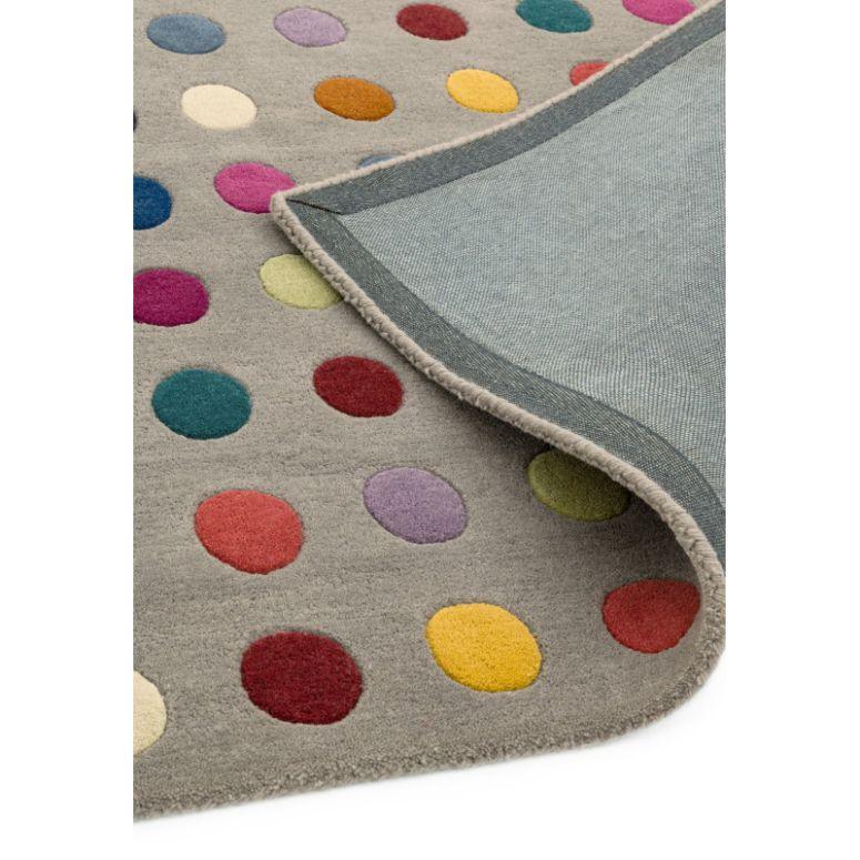 Grey wool rug with multicoloured polka dots and folded corner showing backing