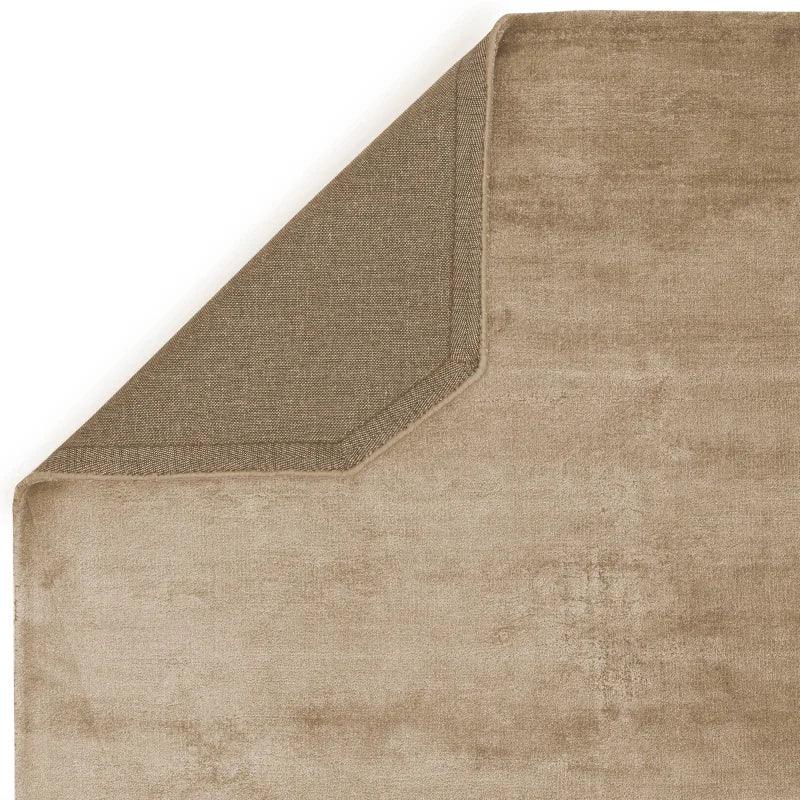 Beige area rug with visible corner showing backing and stitched edge detail
