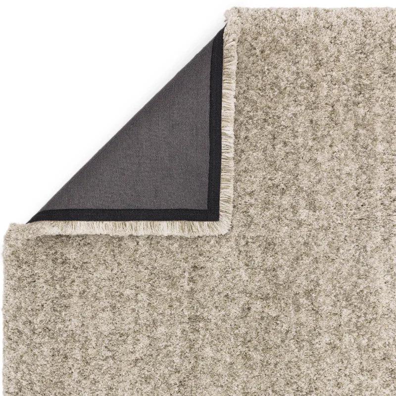 Beige textured rug with fringe and visible black non-slip backing corner