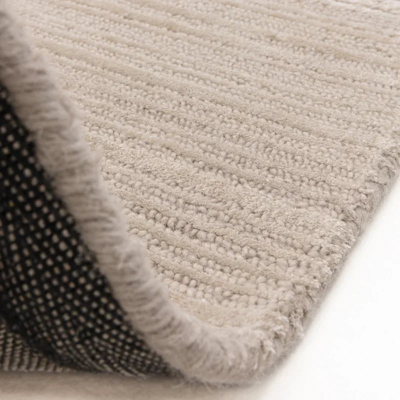 Close-up of beige textured rug with visible pile and non-slip backing