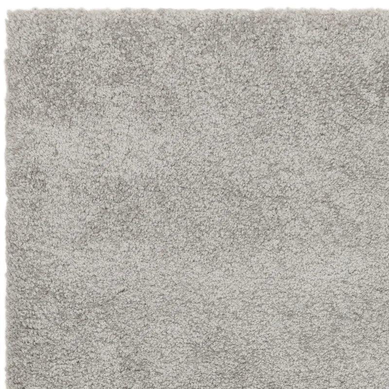 Close-up of light grey shaggy rug texture and pile detail