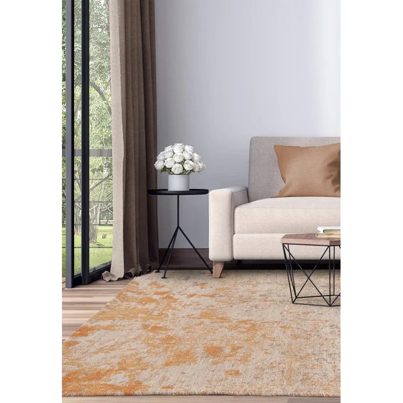 Beige and orange area rug in modern living room with cream sofa and glass side table