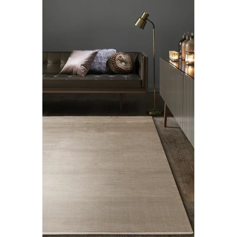 Beige area rug on wooden floor in modern living room with sofa and gold floor lamp