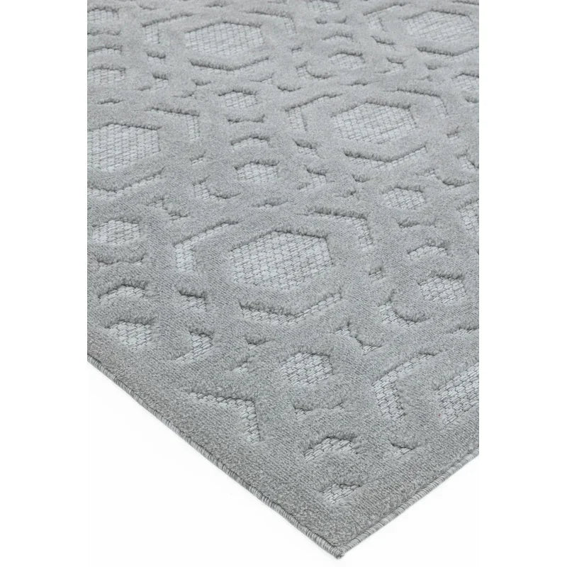 Light grey patterned rug with raised geometric texture, shown at an angled close-up view