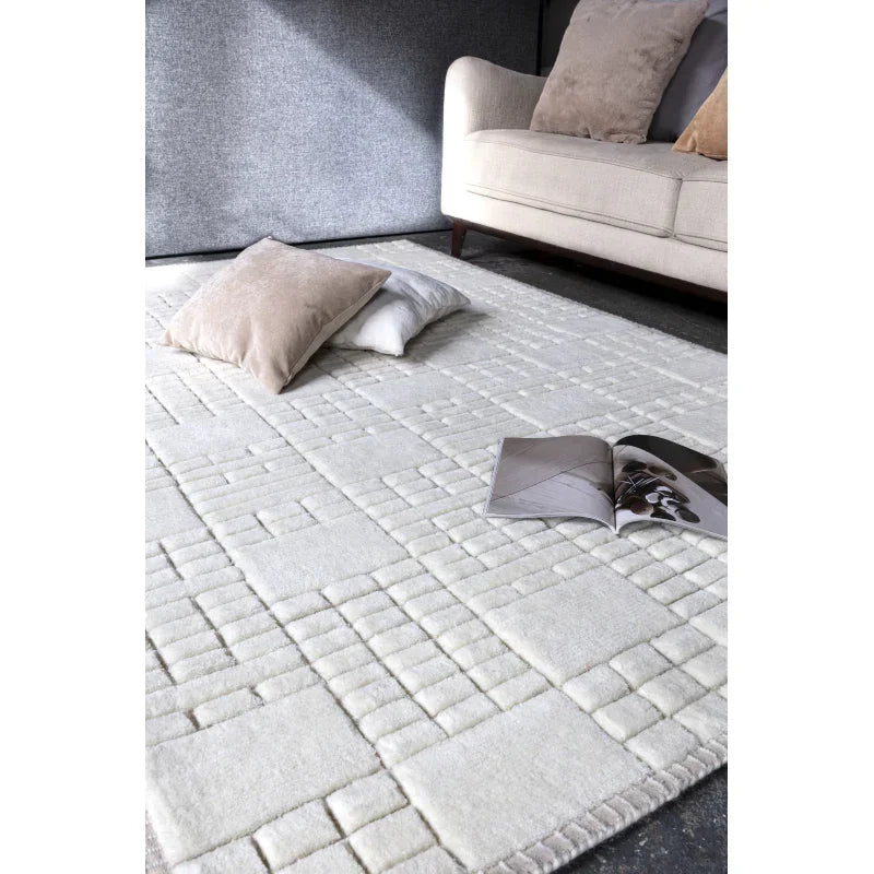 Ivory geometric rug with two scatter cushions and an open magazine beside a cream sofa