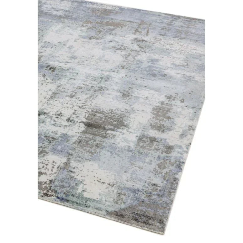 Modern area rug with abstract grey and blue pattern, close-up of corner on white background