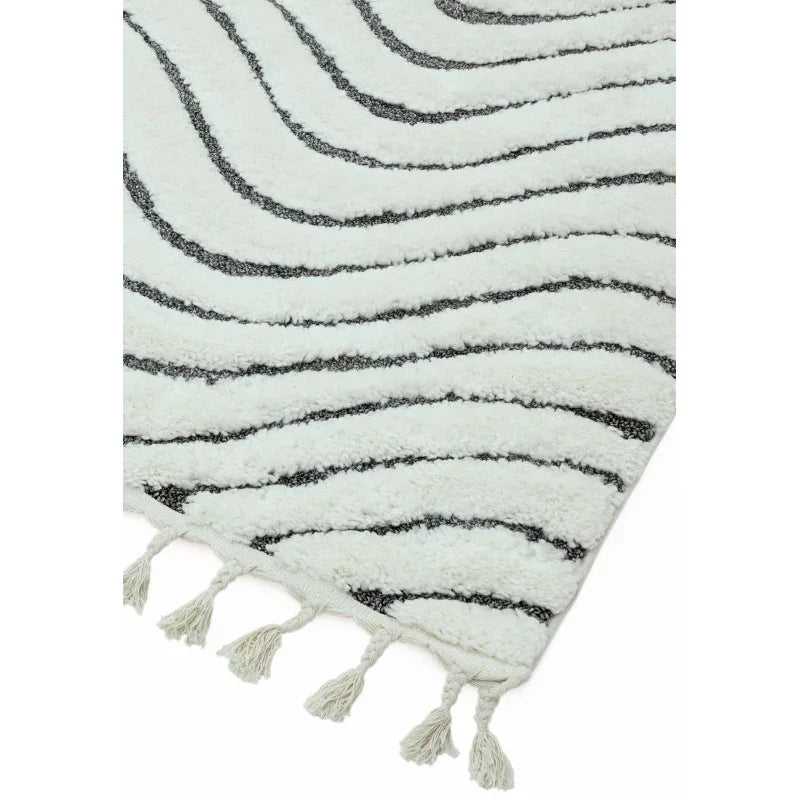 Cream and black wave patterned rug with tassel edge, close-up of corner detail