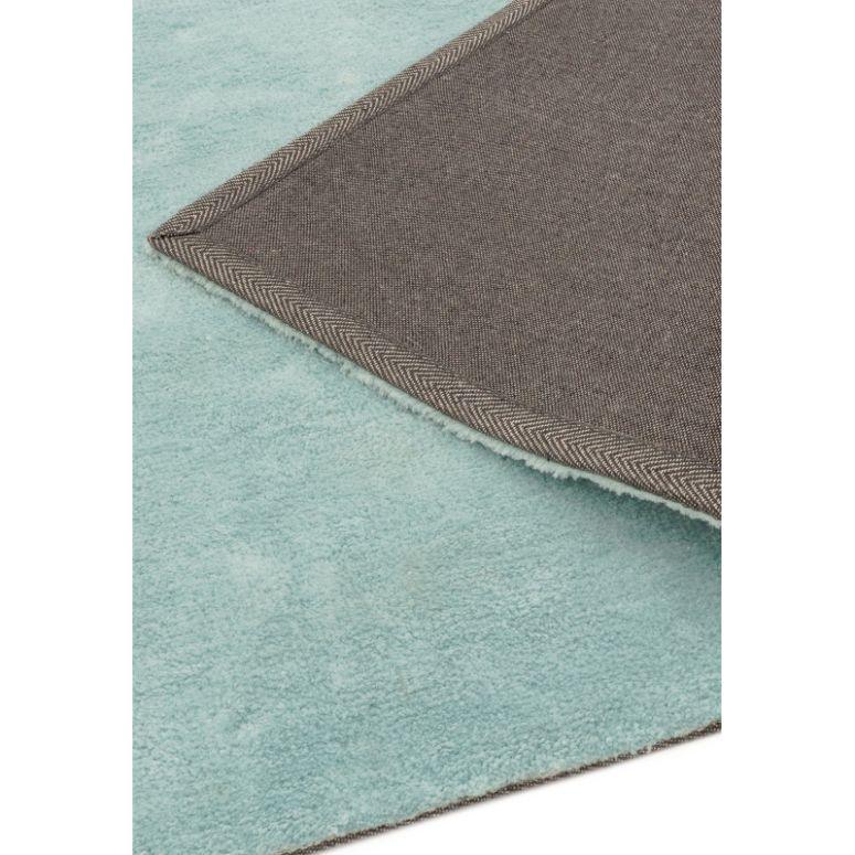 Closeup of light blue area rug with textured backing corner folded over