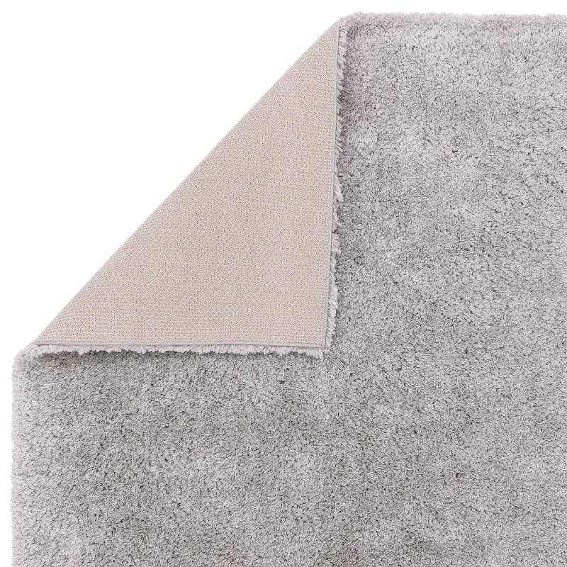 Light grey shaggy rug with one corner flipped to show backing texture