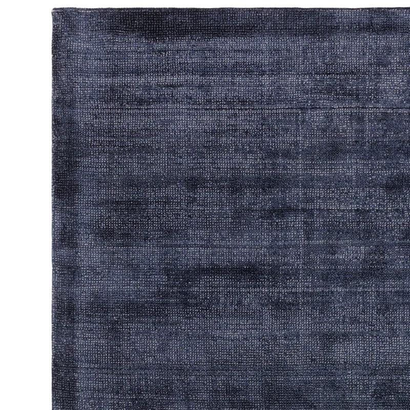 Close-up of dark blue area rug with textured woven pattern and finished edge