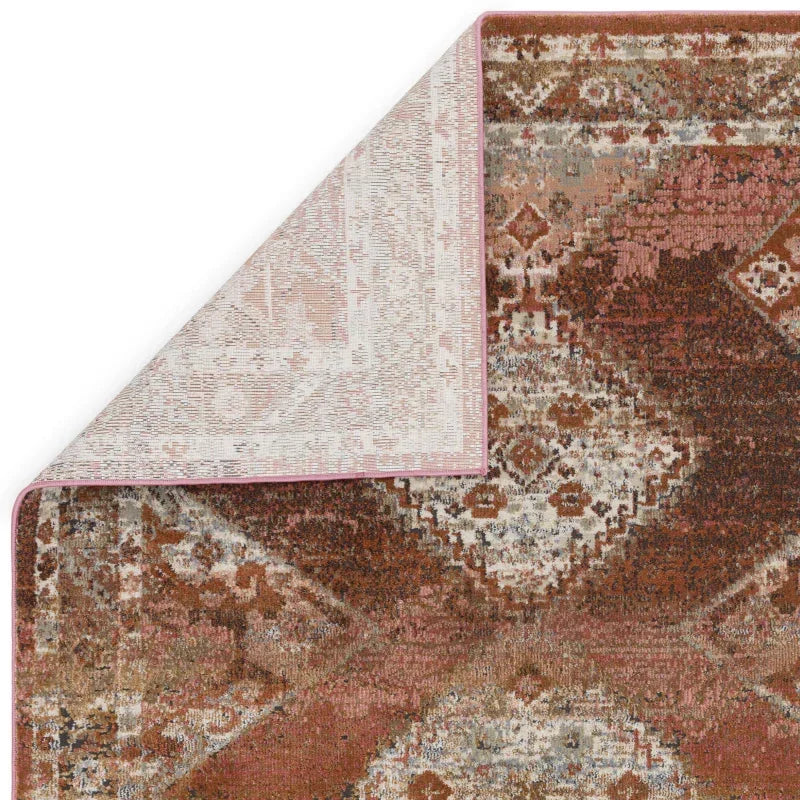 Rust geometric patterned rug with folded corner showing woven texture and underside