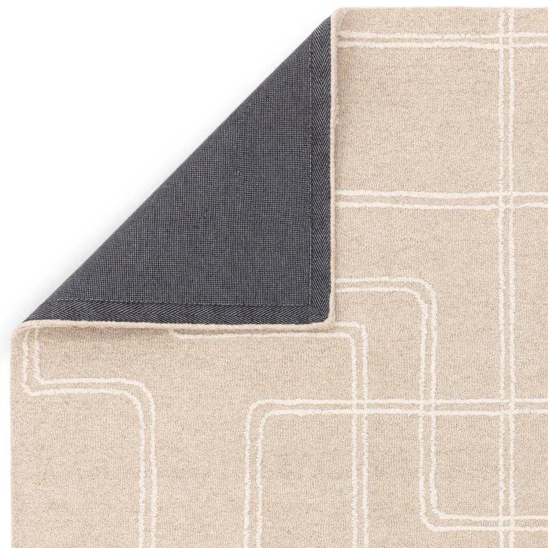 Beige area rug with white geometric lines and folded corner showing dark backing