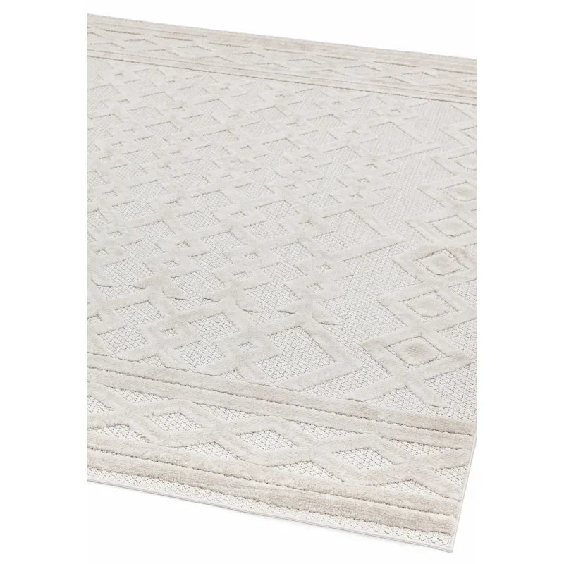 Textured cream area rug with geometric pattern and border detail, close corner view