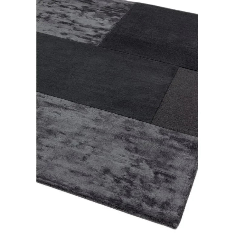 Rectangular area rug with modern grey and black block pattern, close-up corner view