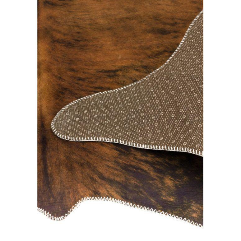Brown faux cowhide rug with stitched edge and non-slip patterned backing