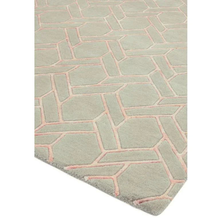 Grey area rug with pink geometric pattern on soft pile, shown from angled corner view
