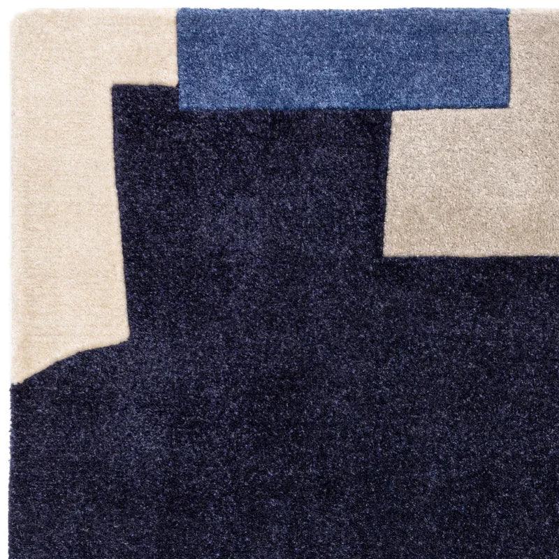 Modern area rug with navy, beige, and blue geometric blocks in close-up view