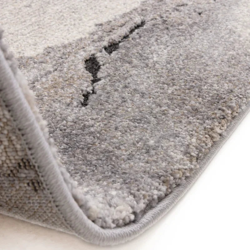 Close-up of thick pile grey and beige area rug with textured surface and stitched edge