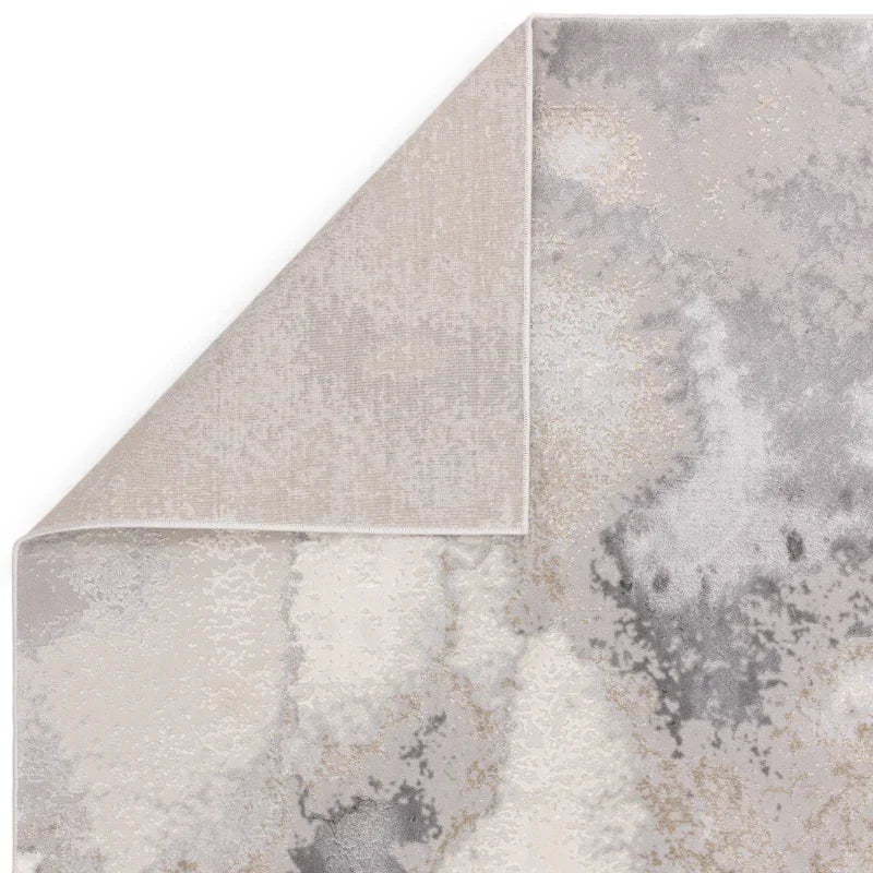 Abstract area rug with grey and beige tones, corner flipped to show backing detail