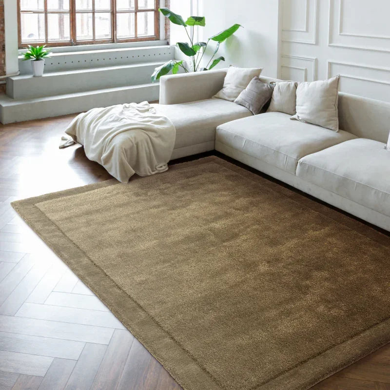 Beige area rug in modern living room with sectional sofa and wooden herringbone floor