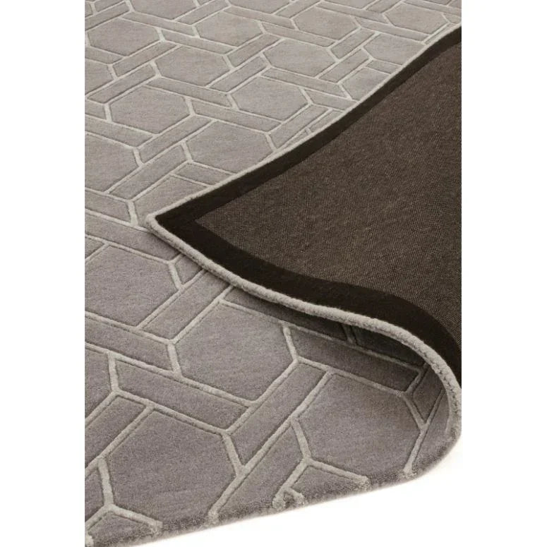 Grey geometric patterned rug with corner flipped to show backing