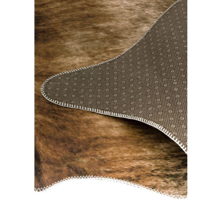 Brown faux cowhide rug with non-slip backing and stitched edge detail