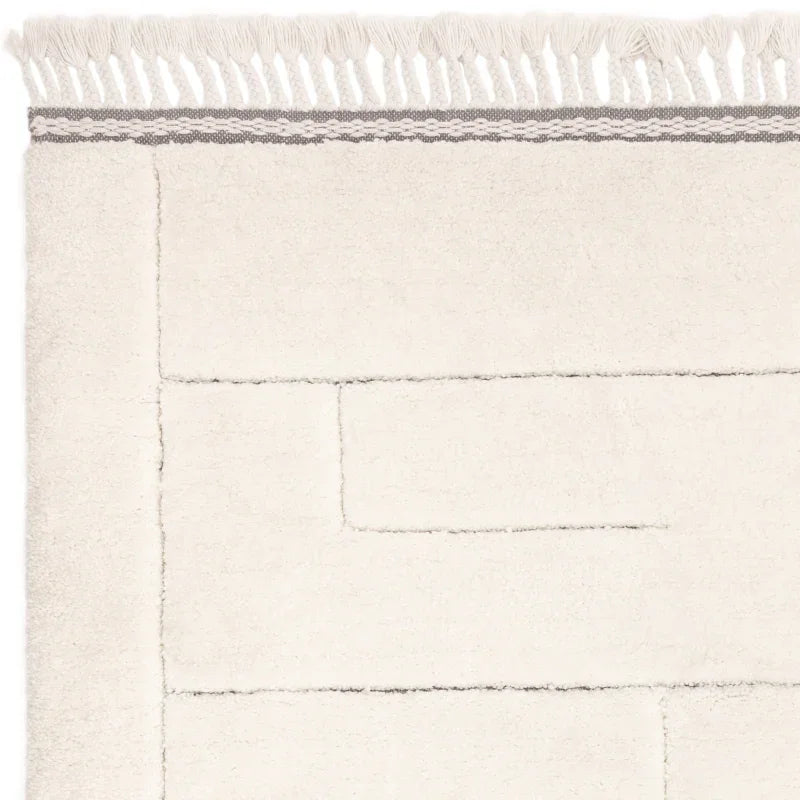 Cream area rug with geometric stitched pattern and fringe border