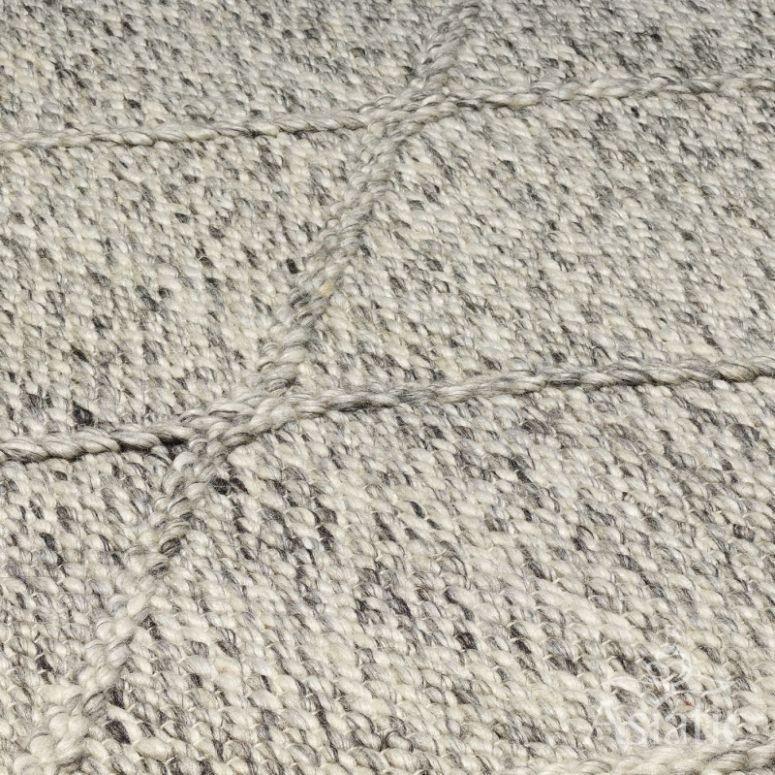 Textured wool rug close-up with neutral tones and handwoven diamond pattern