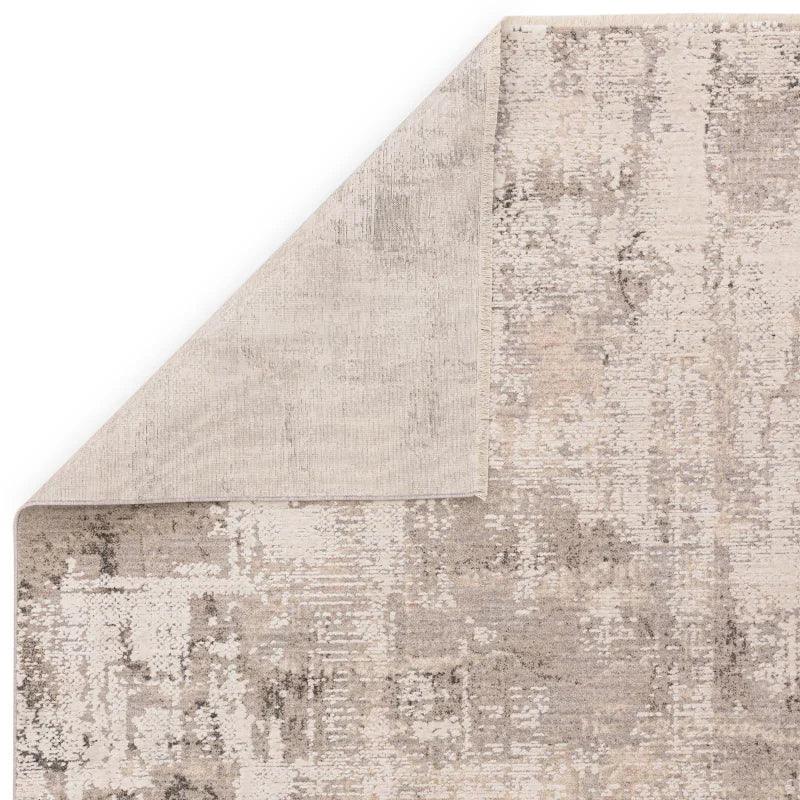 Beige patterned area rug with textured surface and turned corner showing backing