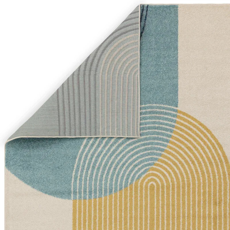 Modern area rug with geometric blue, yellow and cream pattern, corner flipped to show backing