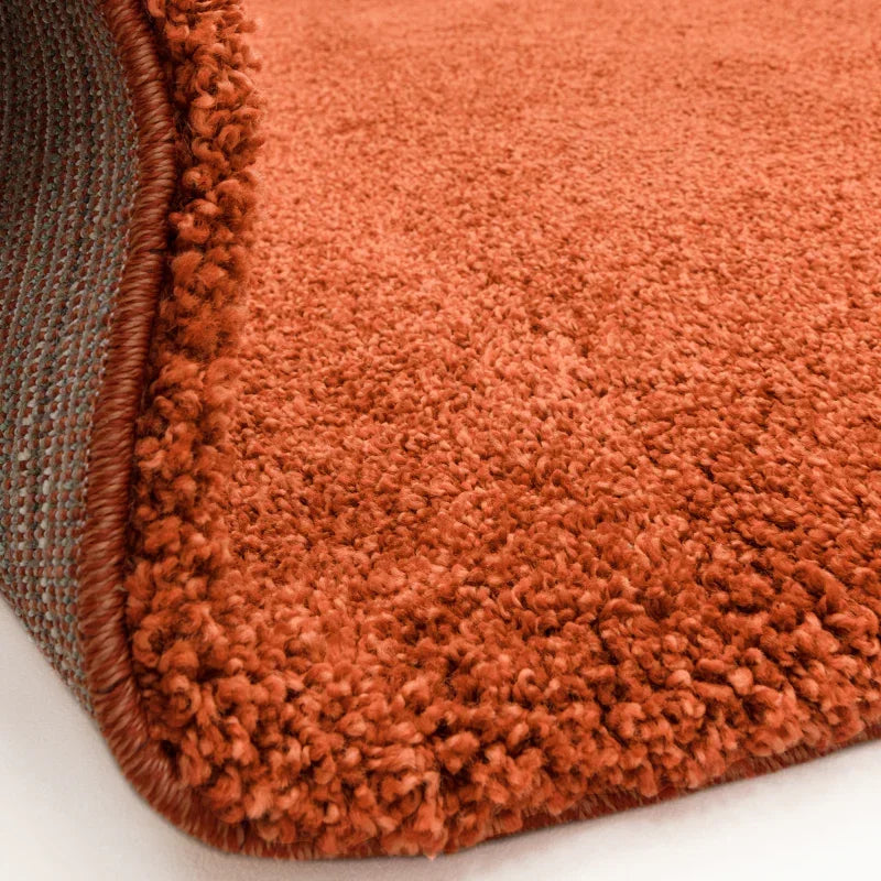 Close-up of orange shaggy rug with thick pile and finished edge