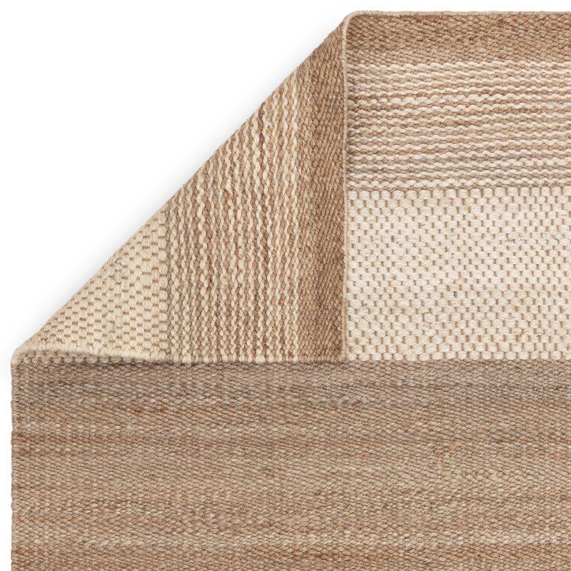 Closeup of beige woven rug corner showing natural fiber texture and pattern