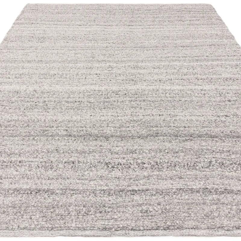 Light grey textured rug with subtle stripe pattern and soft pile, shown from a low angle