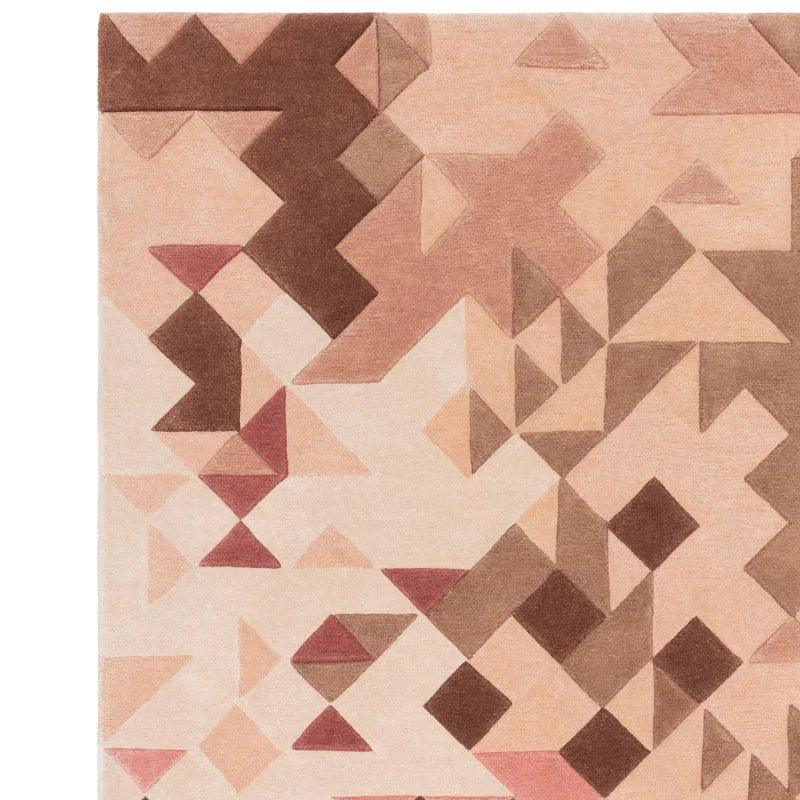 Geometric patterned rug in beige, brown and pink tones with angular abstract shapes