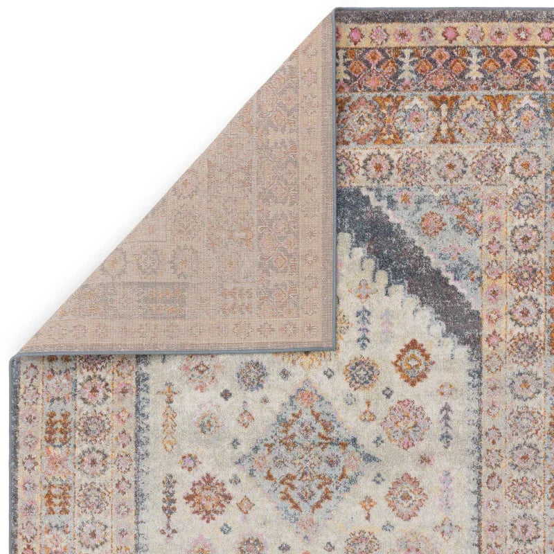 Patterned area rug with cream, grey, and rust tones, corner flipped to show backing