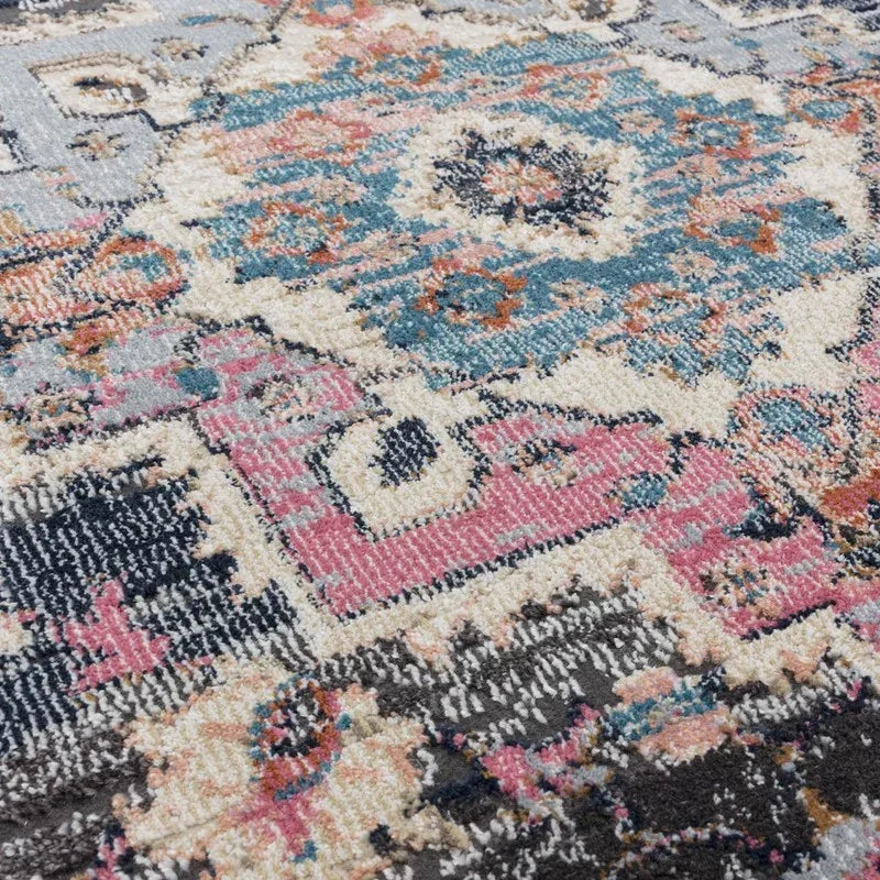 Close view of patterned area rug with blue, pink, and cream geometric design