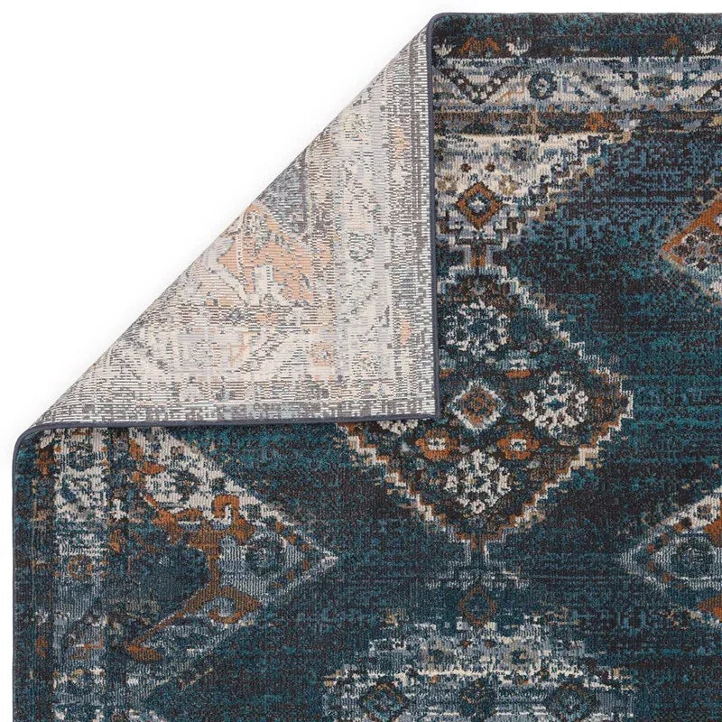Blue and rust patterned rug with corner flipped to show woven backing detail