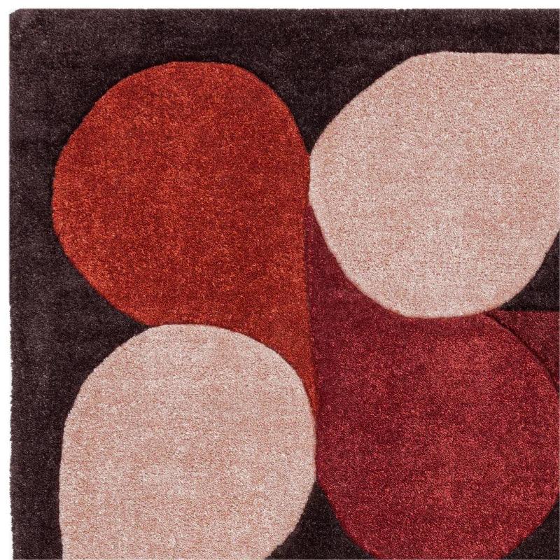 Modern geometric rug with red, beige, and black abstract shapes, close up texture view