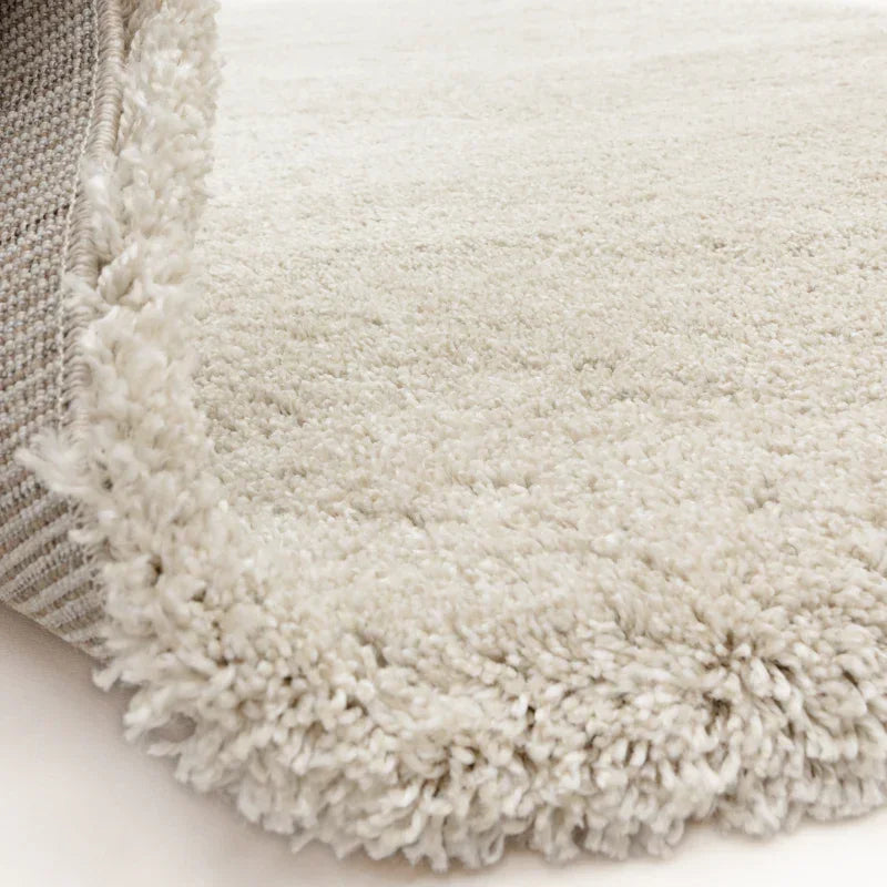 Close view of cream shaggy rug corner showing thick pile and textured backing